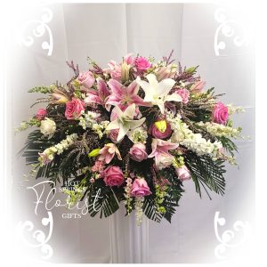 An arrangement of pink lilies, roses, and assorted greenery in a floral display.