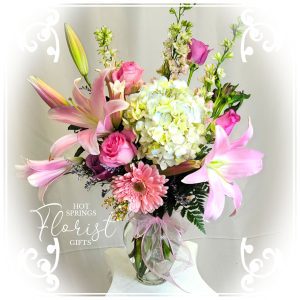 Vibrant Spring 2023 Premium Bouquet 1 with lilies, roses, and hydrangeas in a white vase, embellished with a watermark from Hot Springs Florist & Gifts.