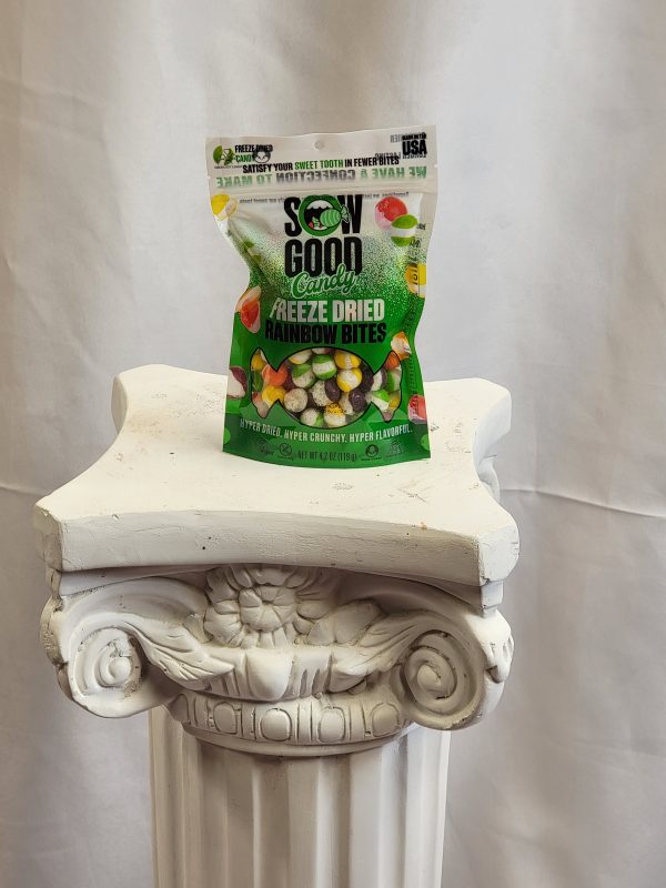 A packet of Sow Good Candy freeze dried rainbow bites rests on a white decorative pedestal.