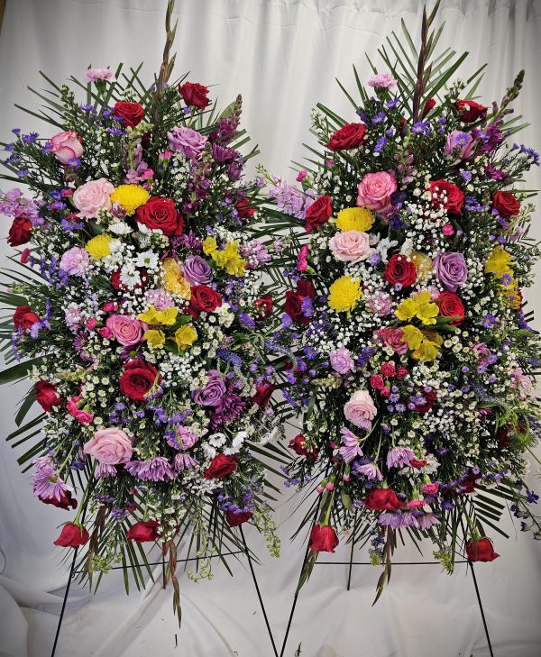 Two large, symmetrical floral arrangements featuring a mix of colorful roses and assorted blooms against a white backdrop.