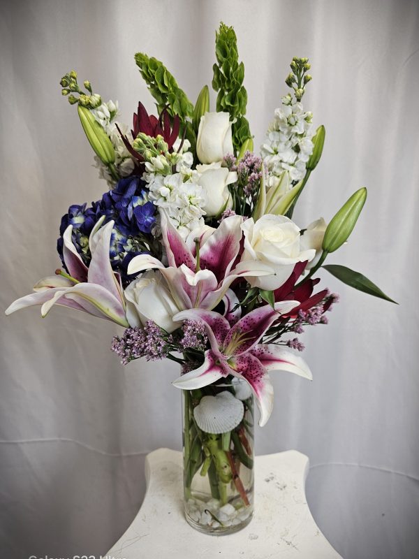 An arrangement of mixed flowers, including lilies and roses, in a glass vase.