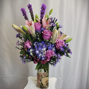 An elegant Cool Water Rose Vase with purple lilies, roses, and hydrangeas in a vase, accented by smaller blue and pink flowers.