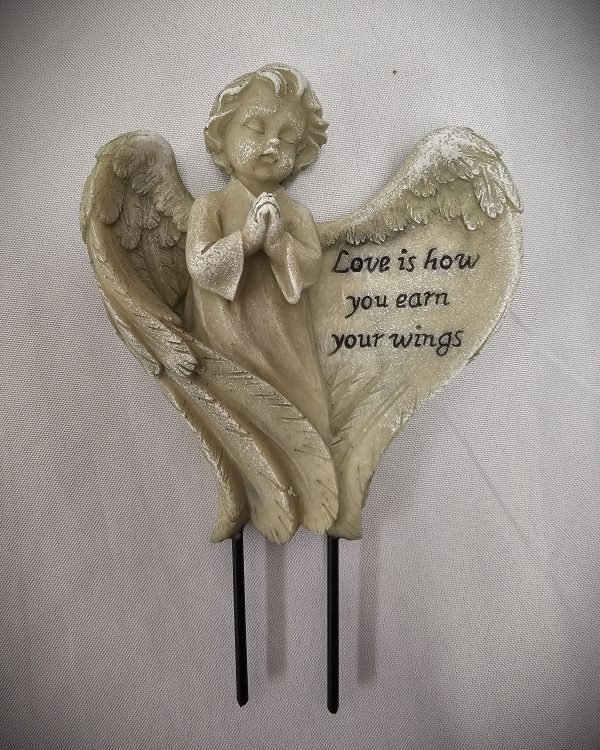 A Sympathy Flower Pot Angel with outspread wings and clasped hands stands in front of a heart-shaped plaque that reads, "Love is how you earn your wings.