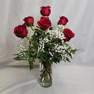 The "Valentine Special: Half Dozen Roses" features a glass vase with six red roses, white baby's breath, and green foliage on a plain white background.